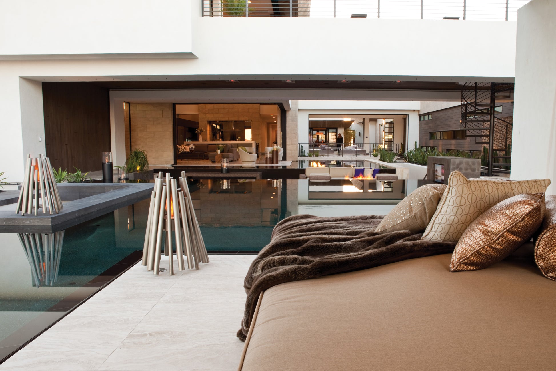 Modern bedroom with bed, pillows, and view of a pool and house exterior.