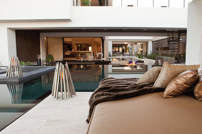 Modern bedroom with bed, pillows, and view of a pool and house exterior.