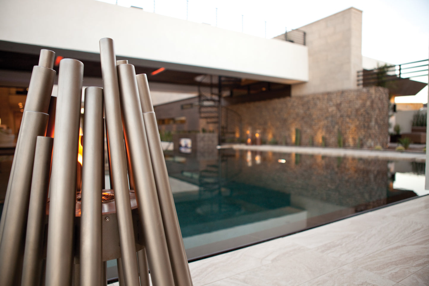 Modern outdoor fireplace with pool and house in the background