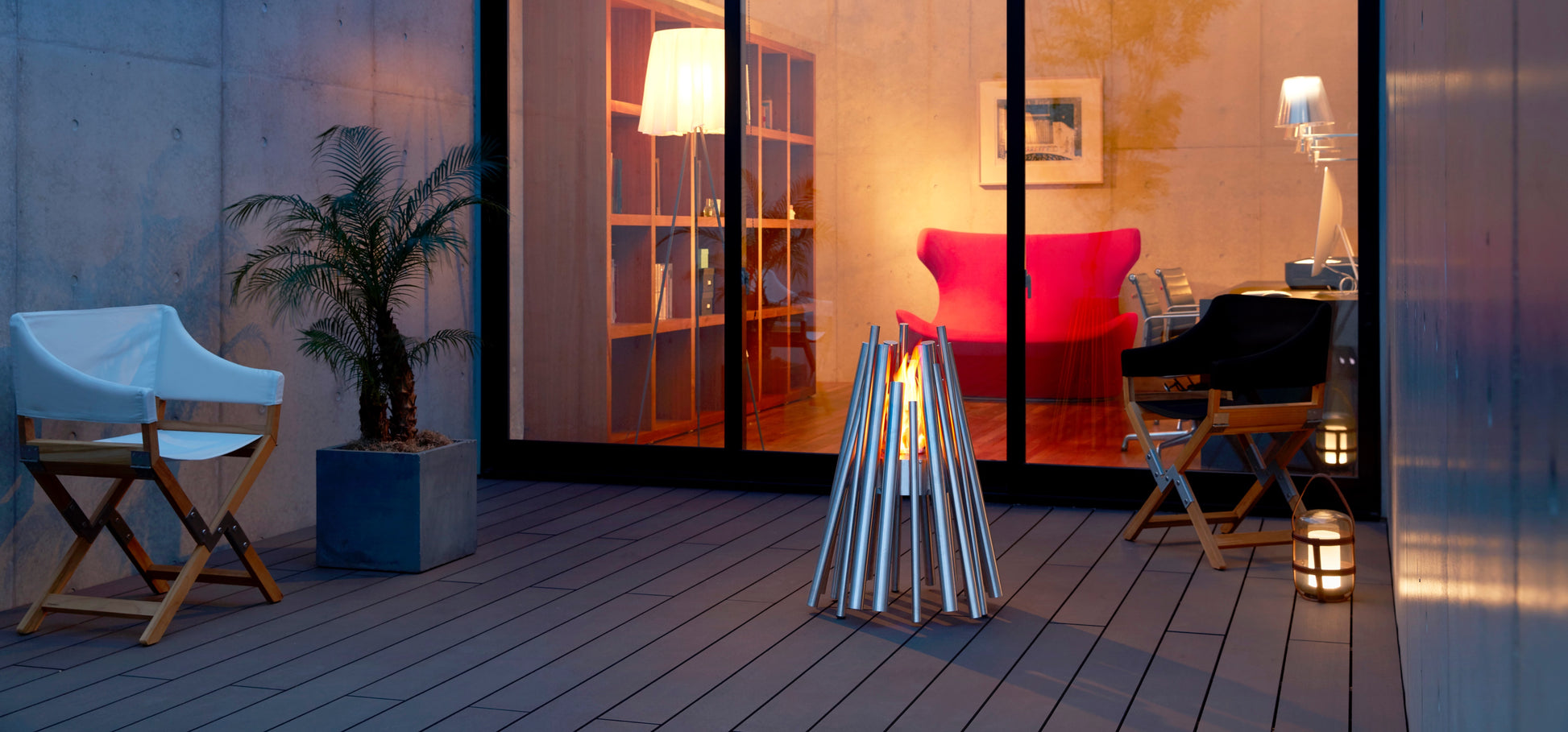 Modern outdoor patio with chairs, a fire pit, and a view into a home interior.