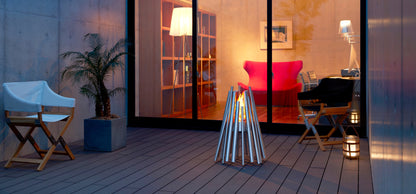 Modern outdoor patio with chairs, a fire pit, and a view into a home interior.