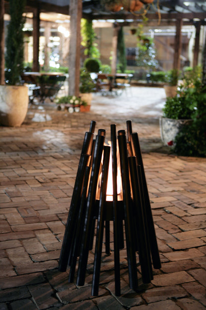 Black metal fire pit on a brick patio with outdoor setting