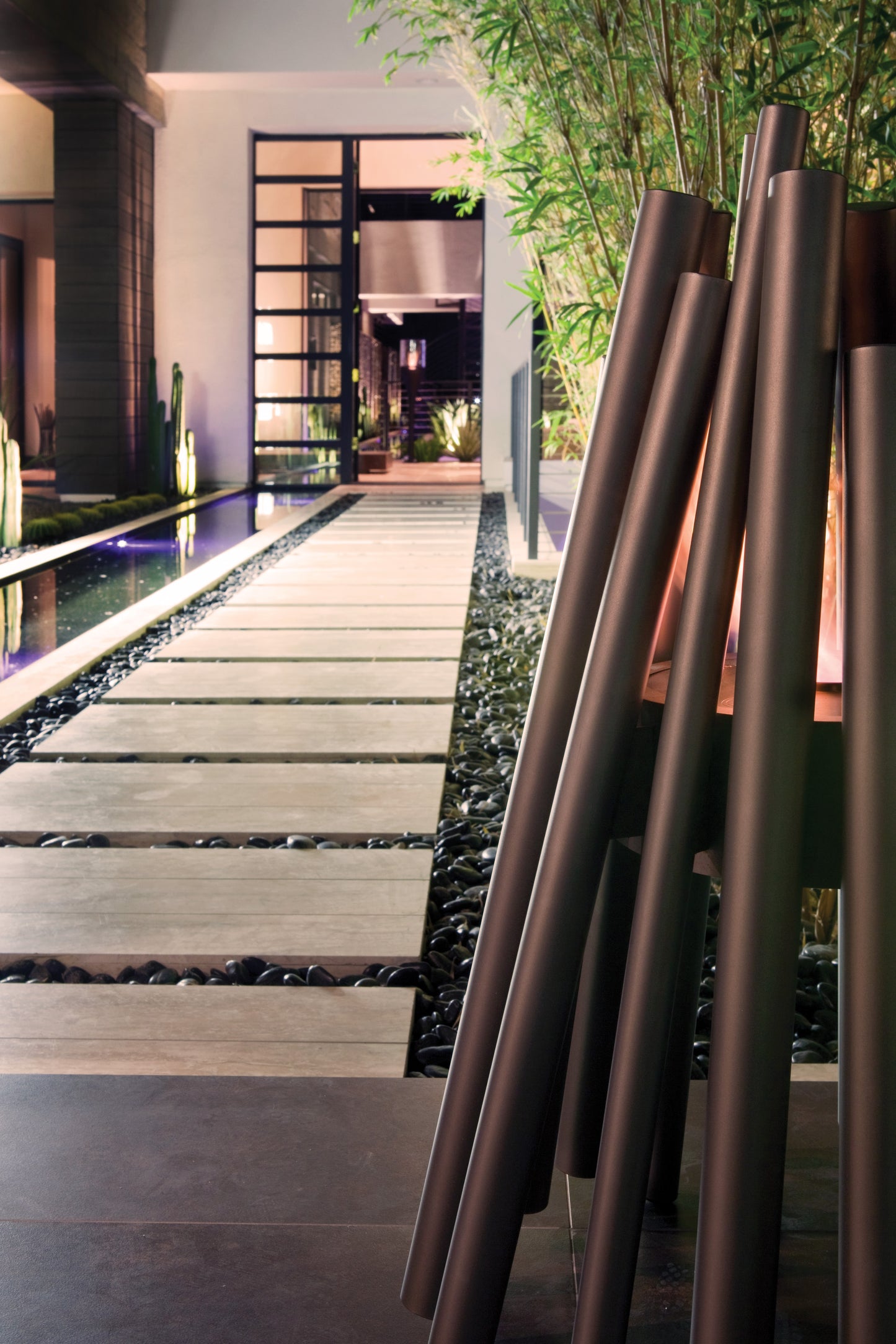 Modern outdoor setting with a pathway, pool, and decorative metal columns.