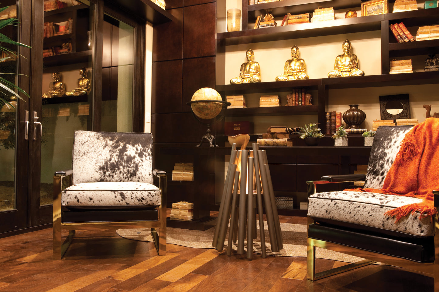 Modern interior with two patterned chairs and a round mirror on a wooden floor.