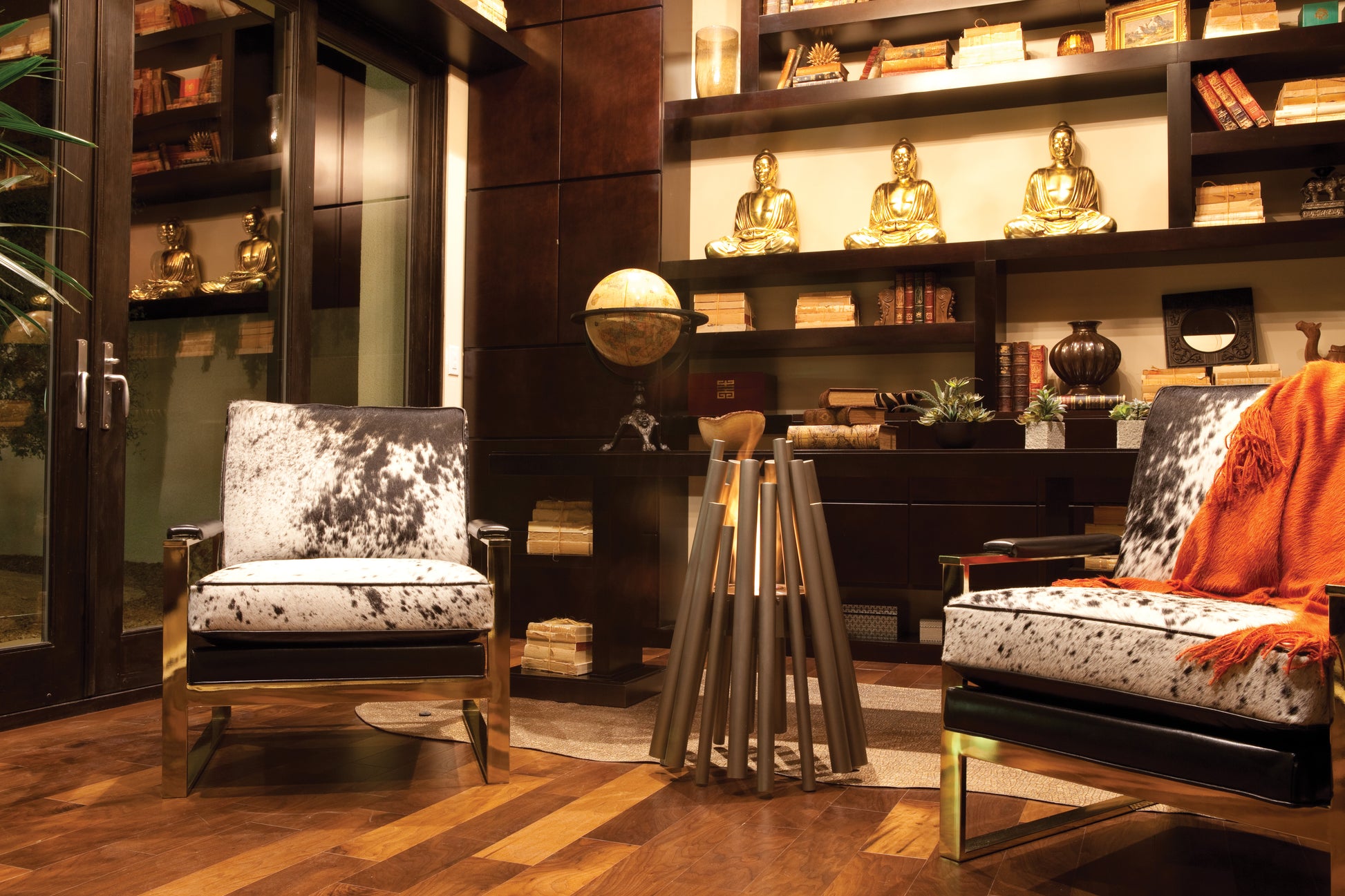 Modern interior with two patterned chairs and a round mirror on a wooden floor.