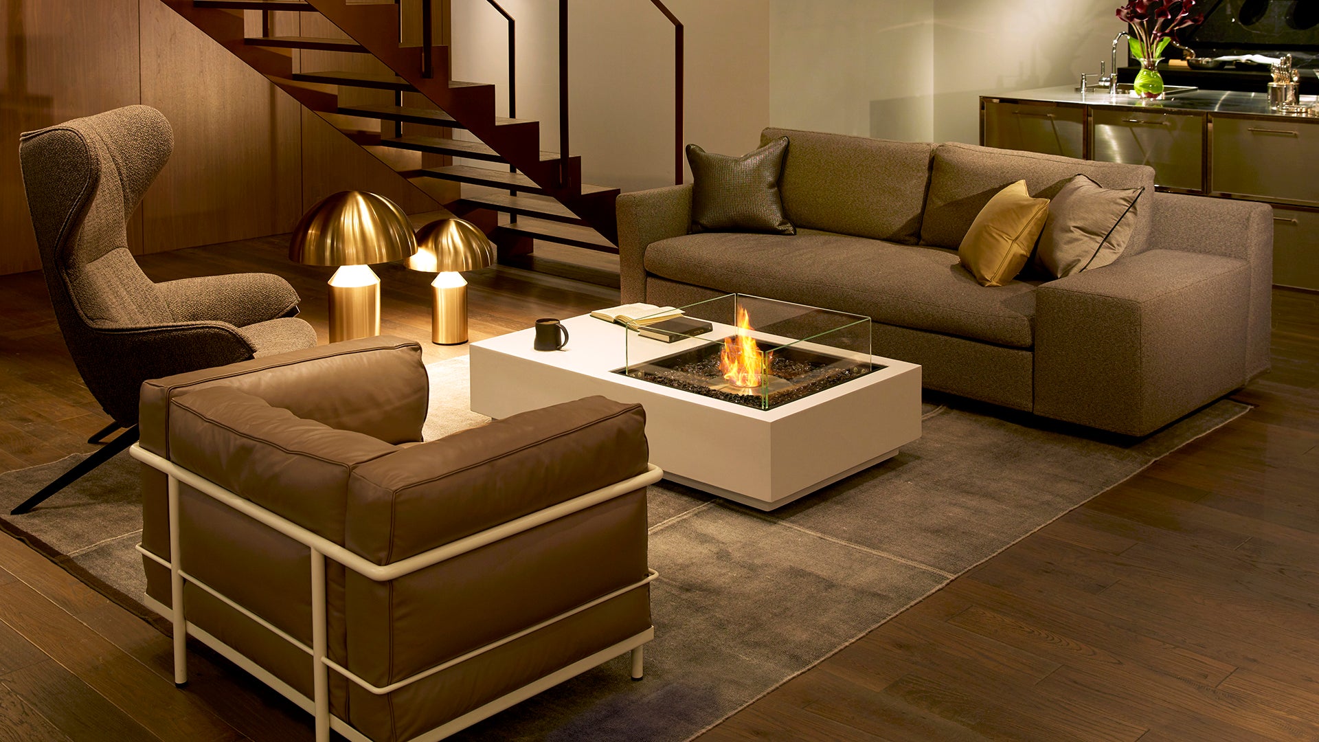 Modern living room with brown sofa, armchair, and coffee table with a fire pit.