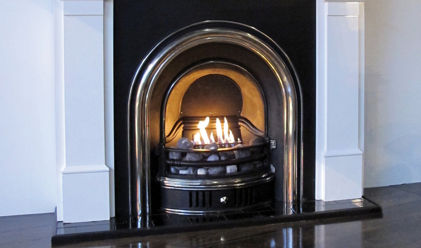 Fireplace with a lit fire inside, surrounded by white walls.