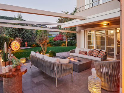 Outdoor patio area with furniture and lighting, featuring a modern house in the background.