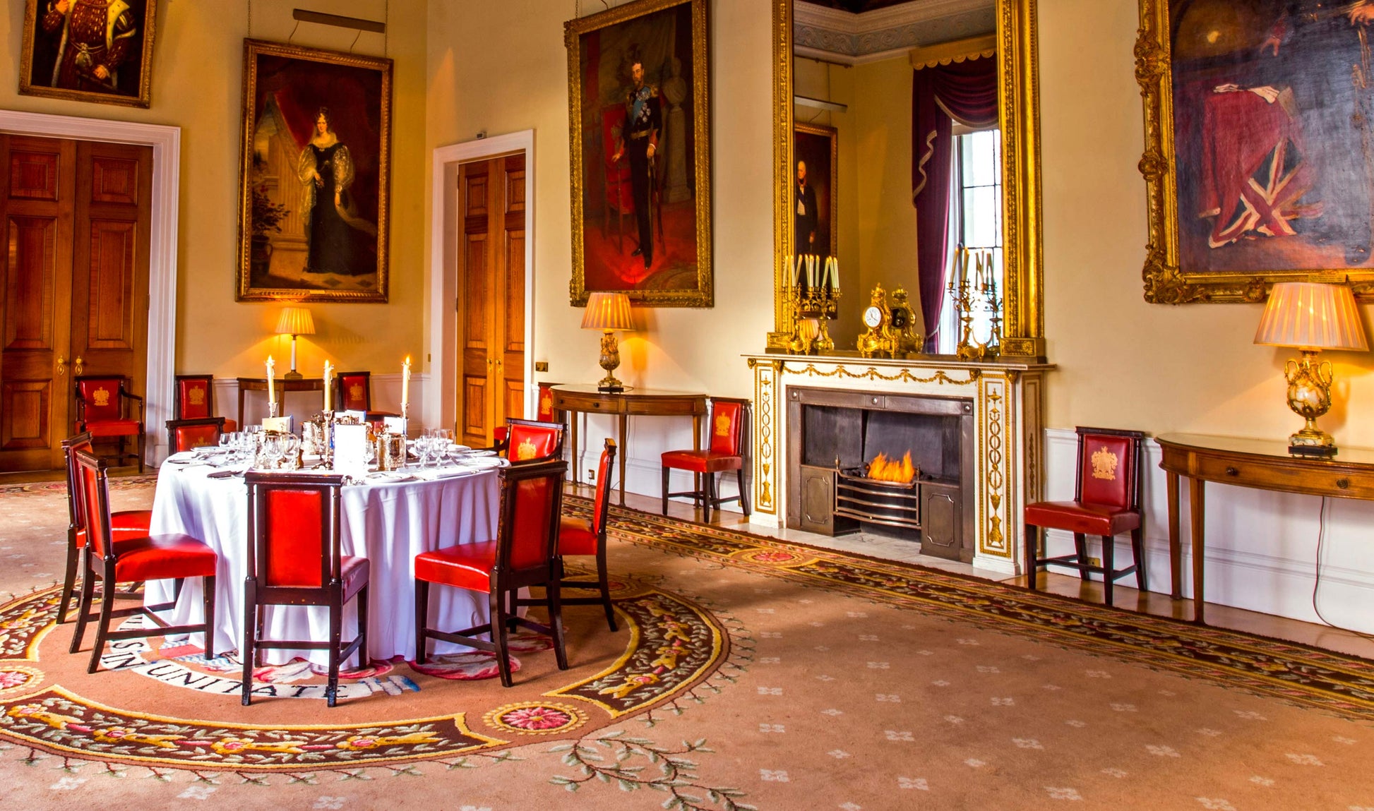 Elegant dining room with red chairs, a round table, and decorative wall art.