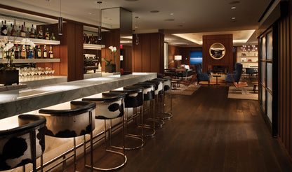 Modern bar interior with stools and a well-stocked bar.