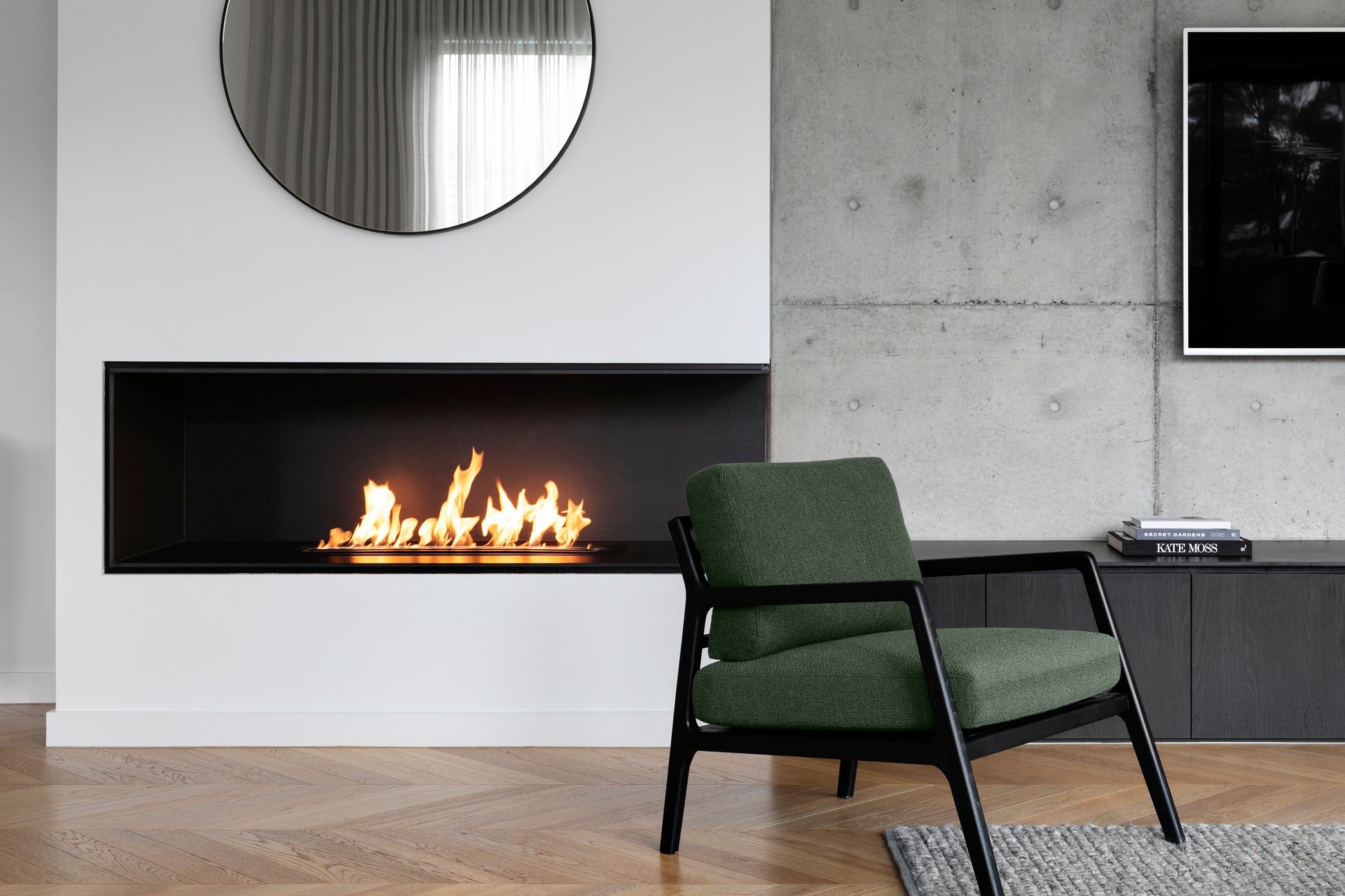 Modern living room with a green armchair, fireplace, and concrete wall.