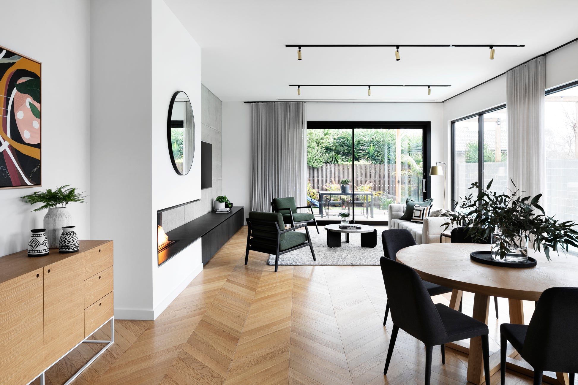 Modern living room with wooden floor, furniture, and large windows.