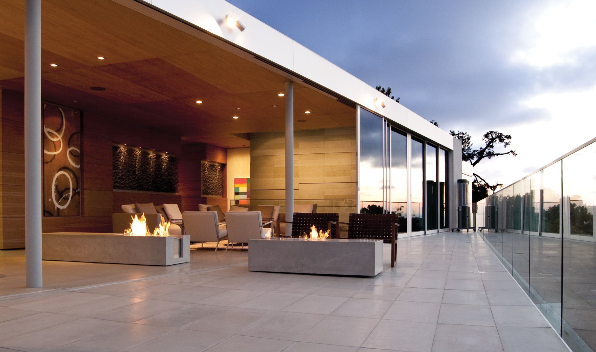 Modern outdoor patio with fire pits and glass walls