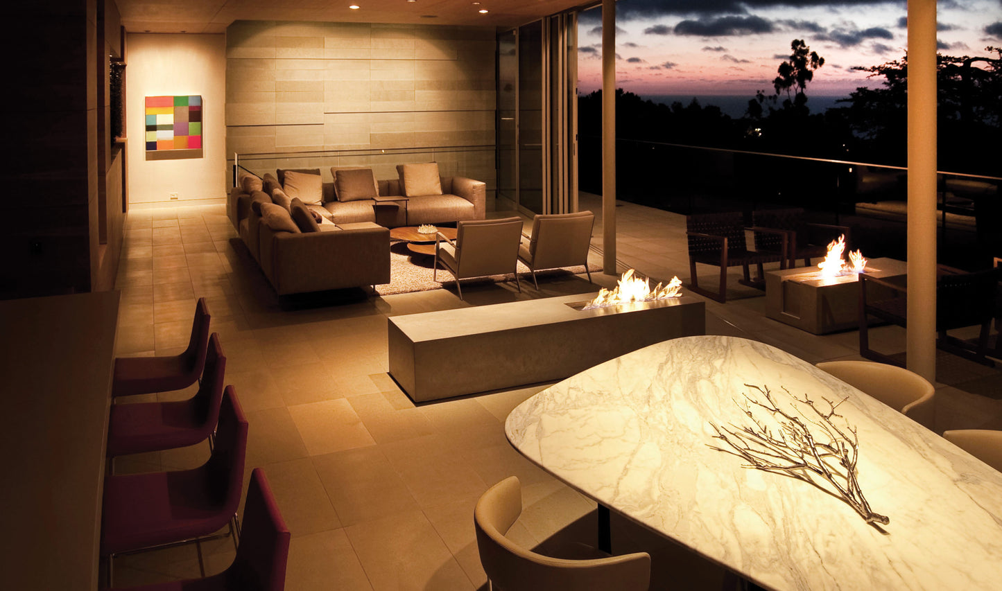 Modern outdoor living space with seating area, fire pit, and table at dusk.