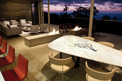 Modern outdoor dining area with a fire pit and scenic view at dusk.