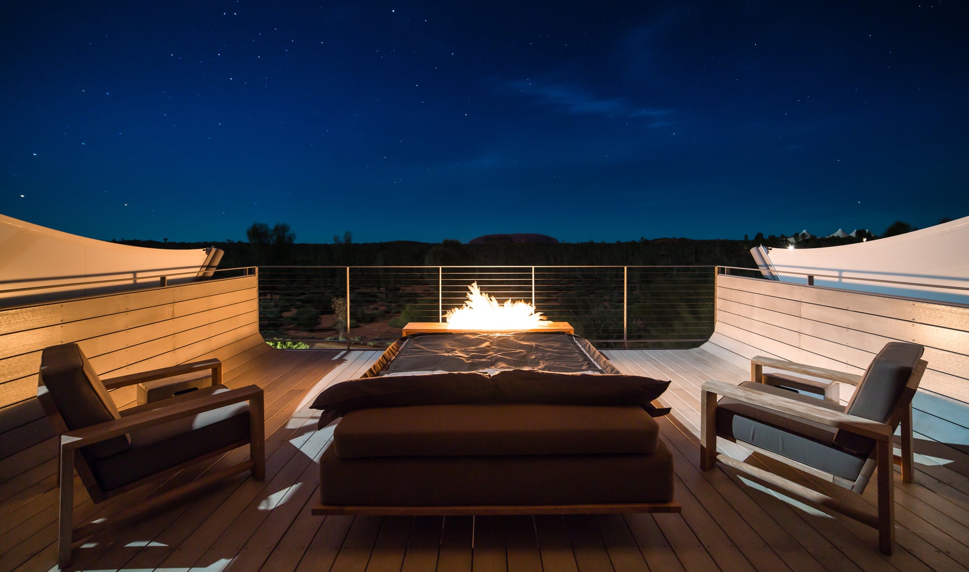 Outdoor deck with fire pit and chairs under a starry night sky