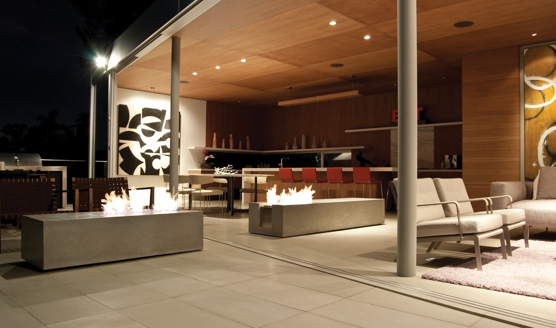 Modern outdoor patio with fire pits and seating area at night