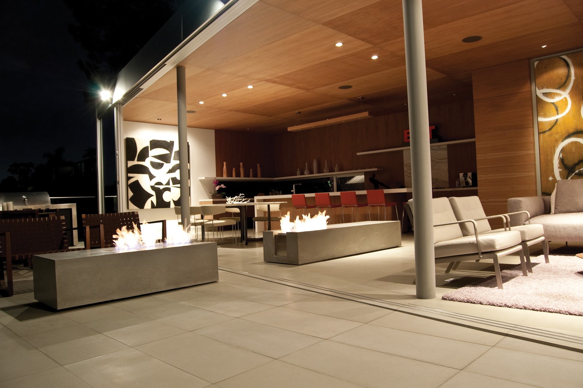 Modern outdoor patio with fire pits and seating area at night