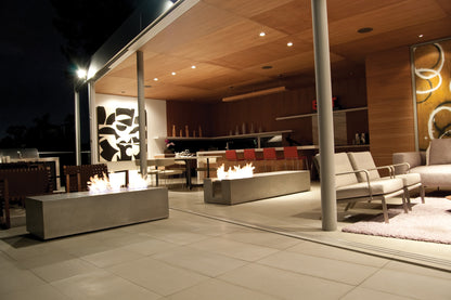 Modern outdoor patio with fire pits and seating area at night