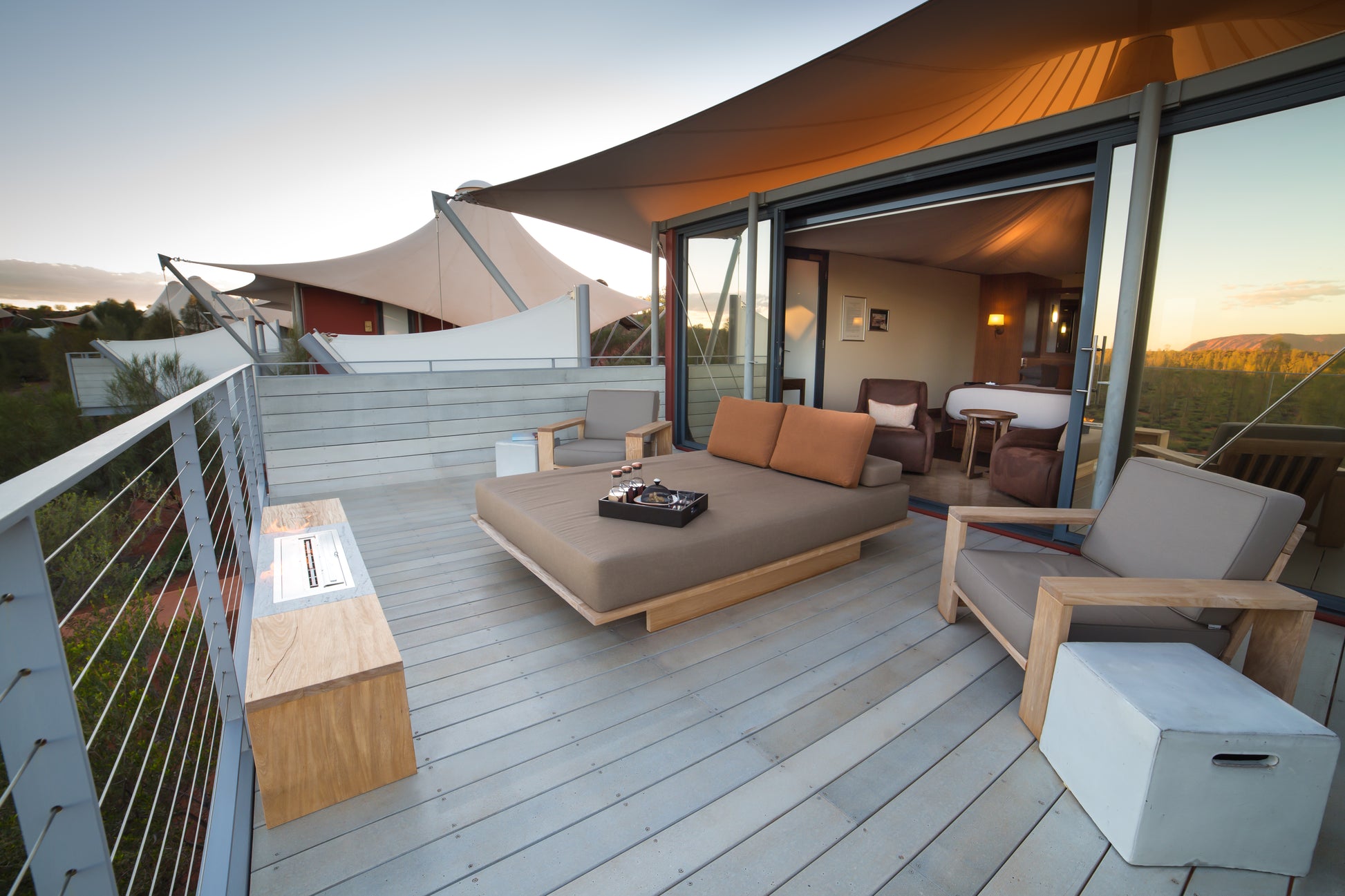 Modern outdoor living space with a couch, chairs, and fire pit on a wooden deck.