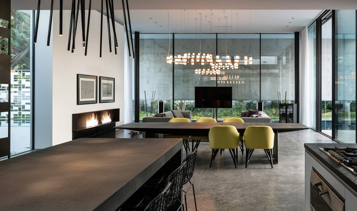 Modern kitchen with large windows, yellow chairs, and a fireplace.
