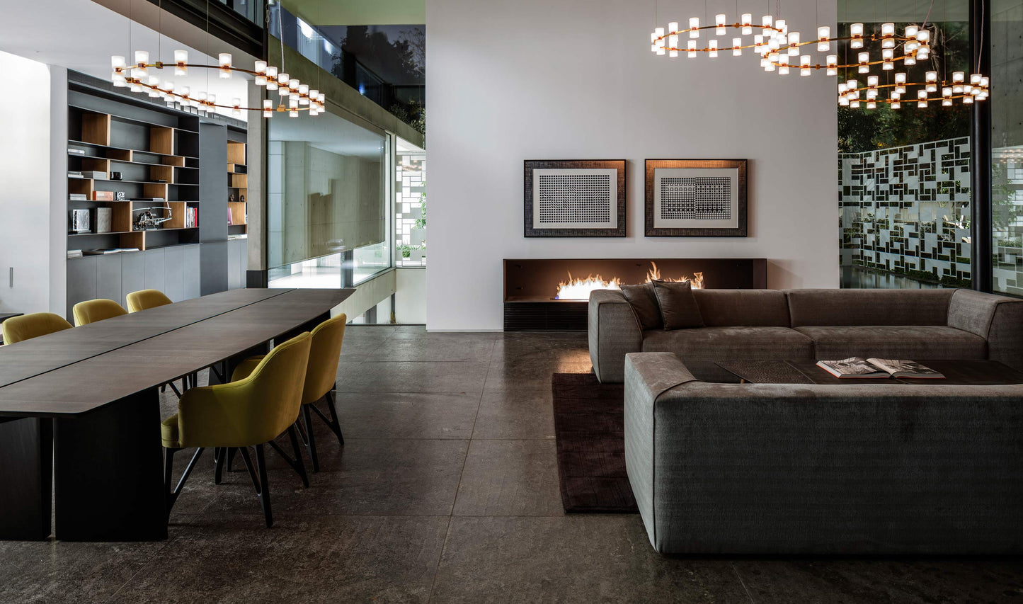 Modern living room with a long dining table and chairs, and a sofa.