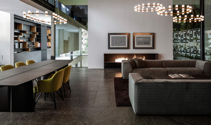 Modern living room with a long dining table and chairs, and a sofa.