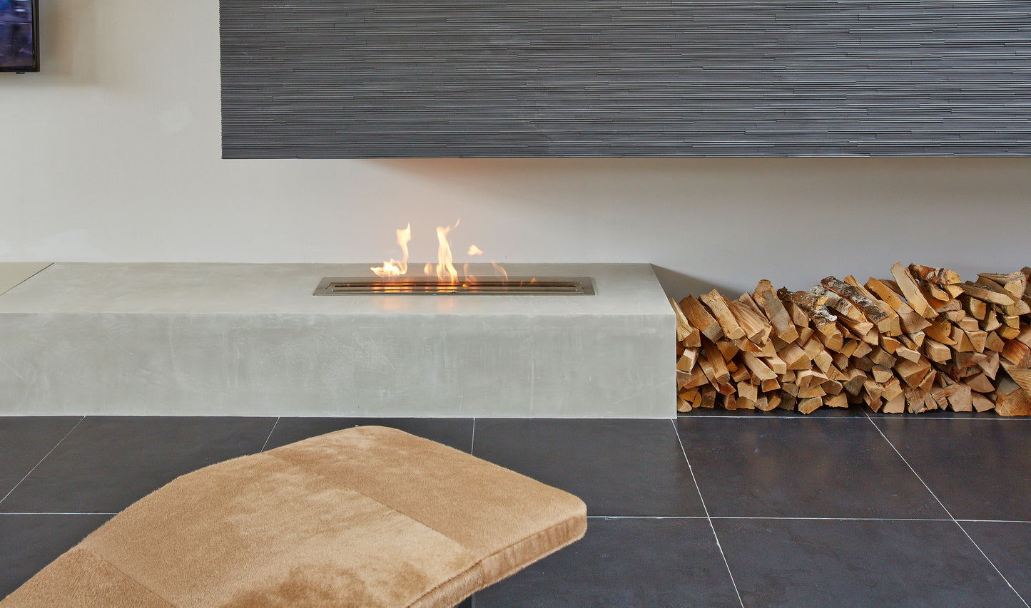 Modern fireplace with concrete bench and stacked wood in a room with gray tiles.