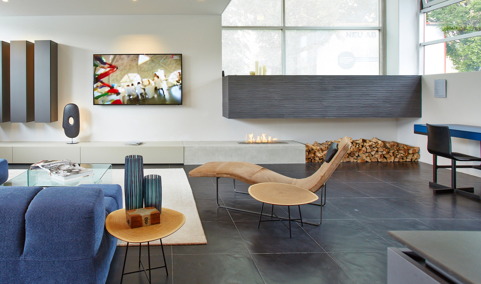 Modern living room with blue sofa, glass coffee table, and wall-mounted TV.