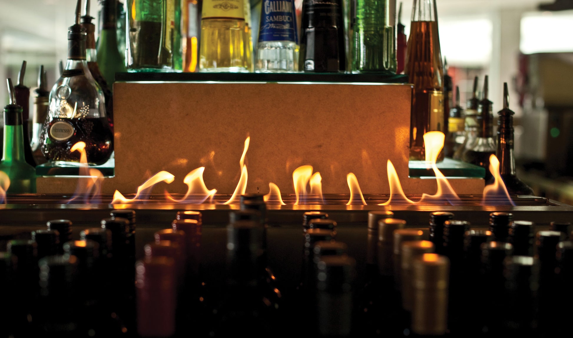 Bottles of alcohol on a bar with a fire feature