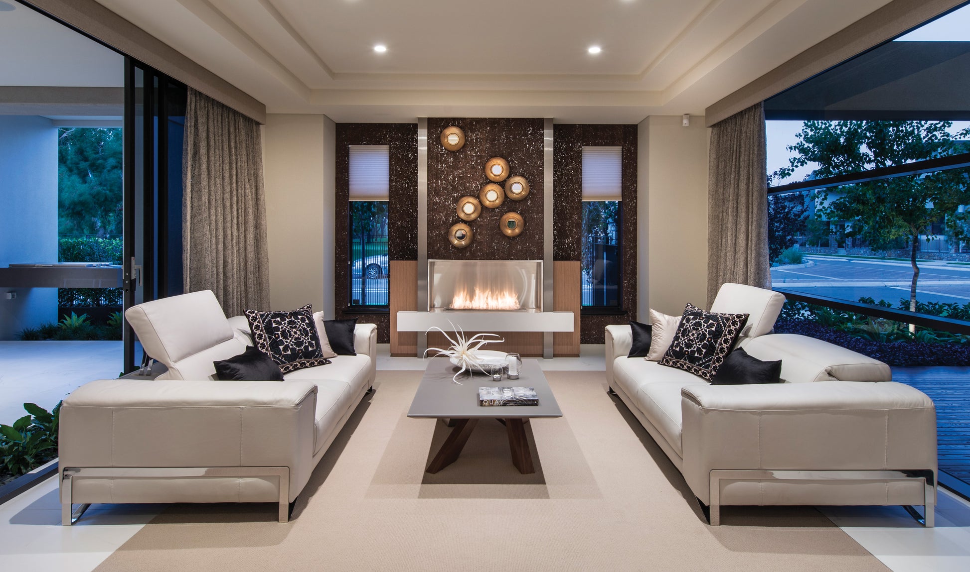 Modern living room with white sofas, a coffee table, and decorative elements.