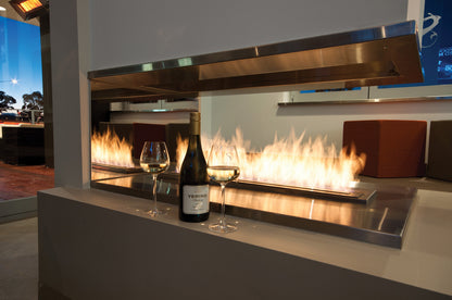 Modern outdoor fireplace with flames, wine bottle, and glasses on a countertop.