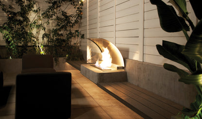 Modern outdoor setting with a fire pit, chairs, and plants.