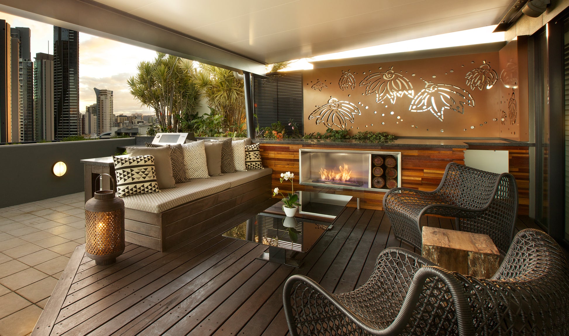 Modern outdoor patio with seating area, fireplace, and city skyline view.