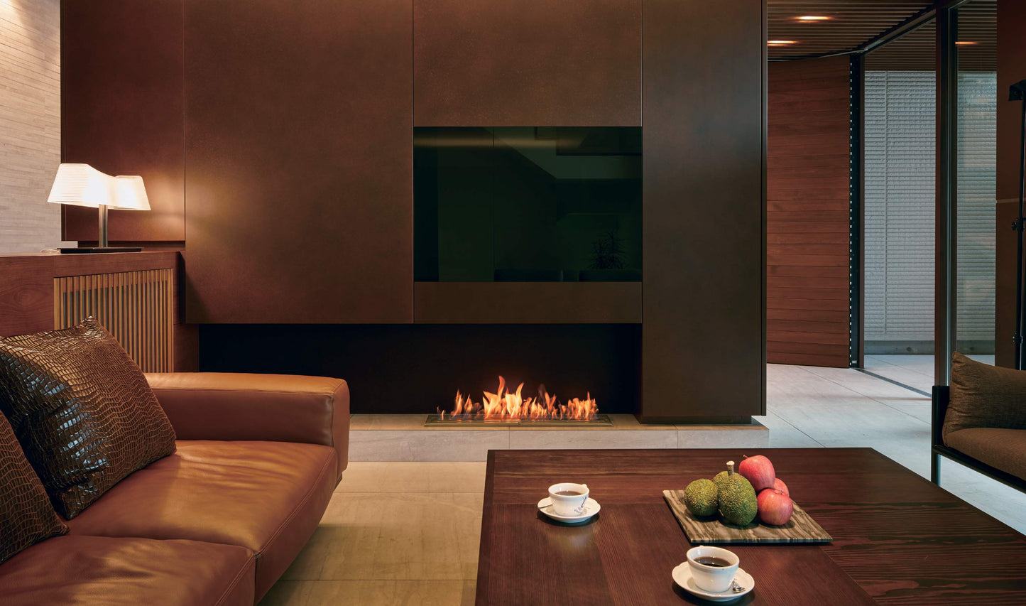 Modern living room with a fireplace, brown sofa, and coffee table with snacks.
