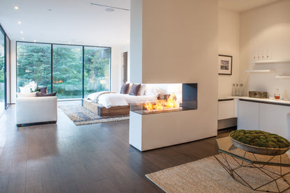 Modern living room with a fireplace, bed, and kitchen area.