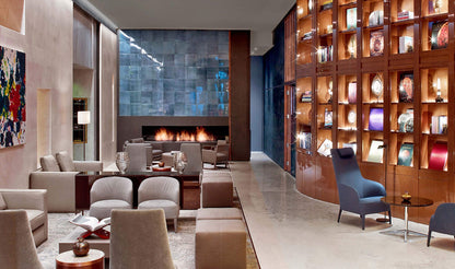 Modern hotel lobby with seating area, fireplace, and bookshelf.