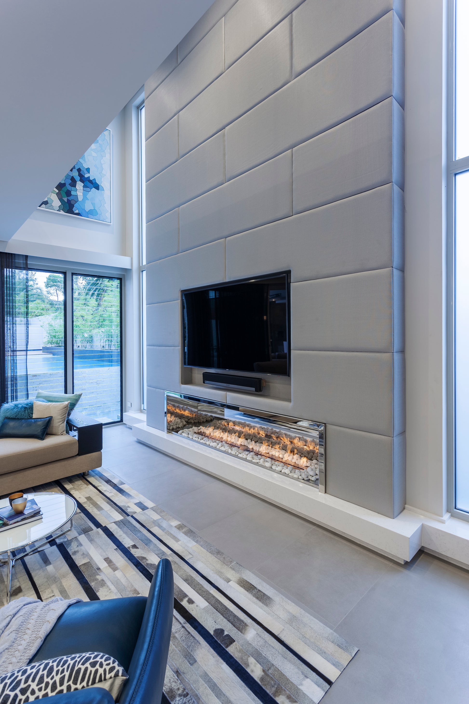 Modern living room with a fireplace and television embedded in a gray paneled wall.