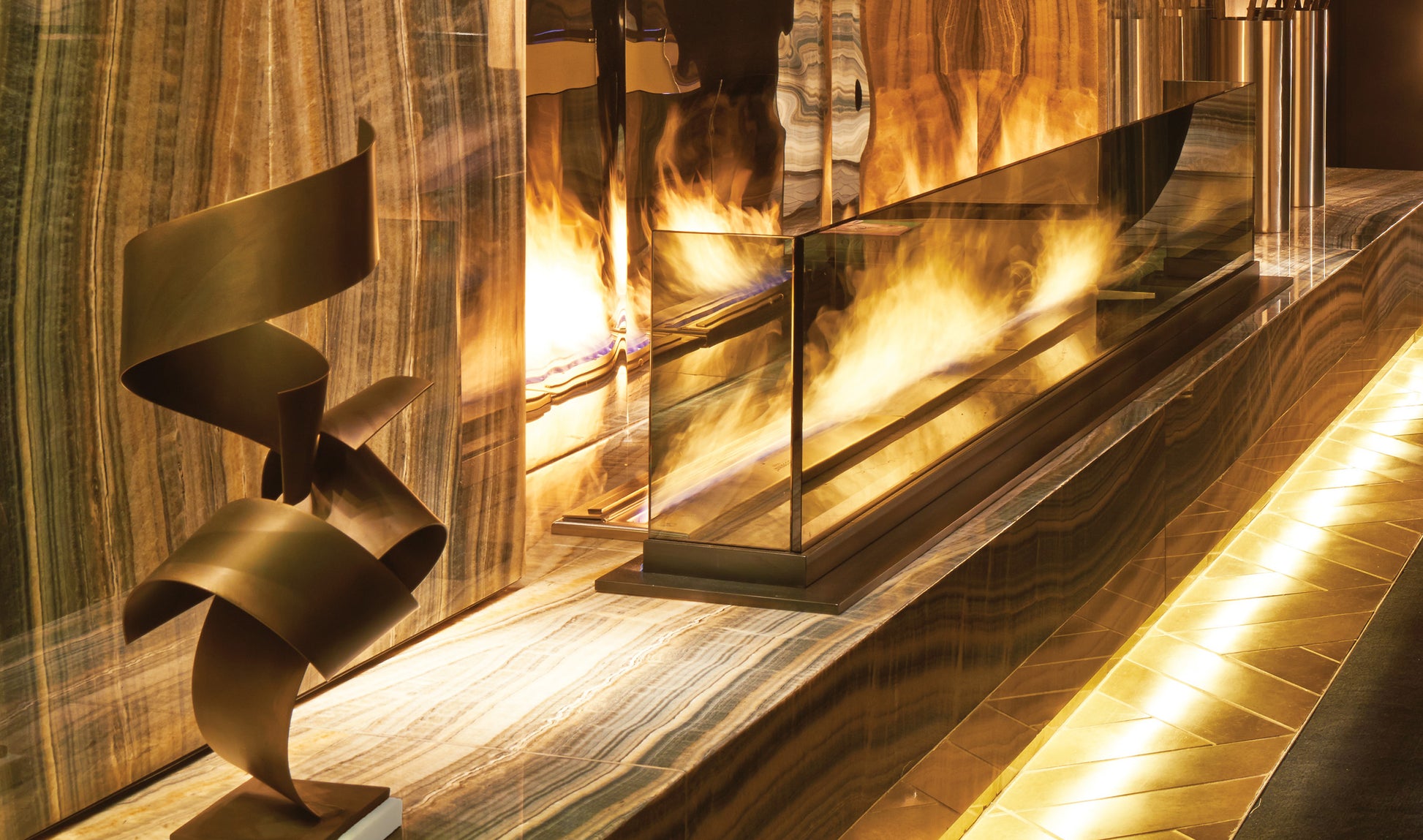 Modern fireplace with glass panel and decorative metal sculpture.