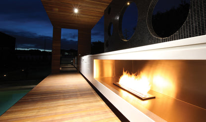 Modern outdoor fireplace with wooden deck at night