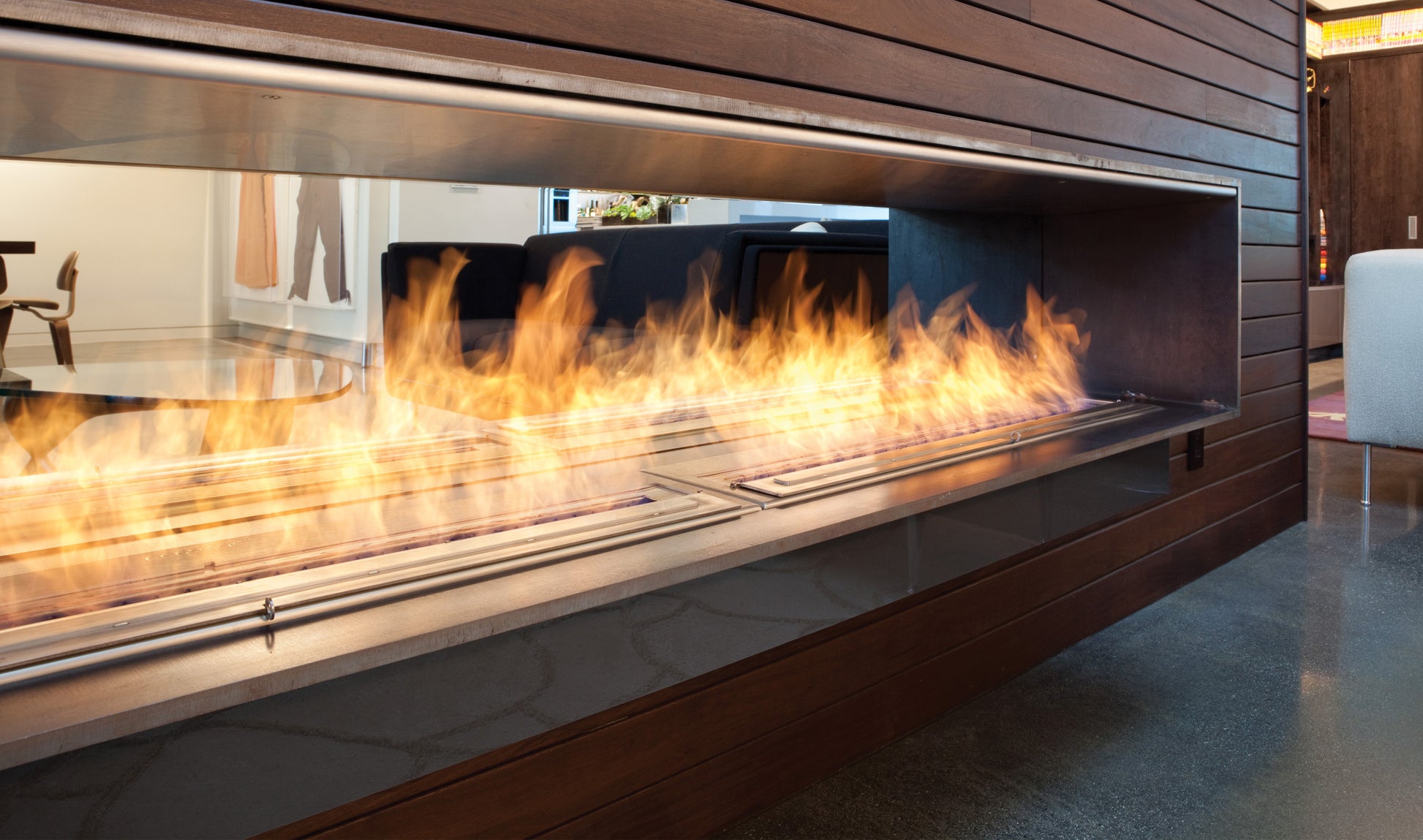 Modern fireplace with flames inside a glass enclosure in a room.