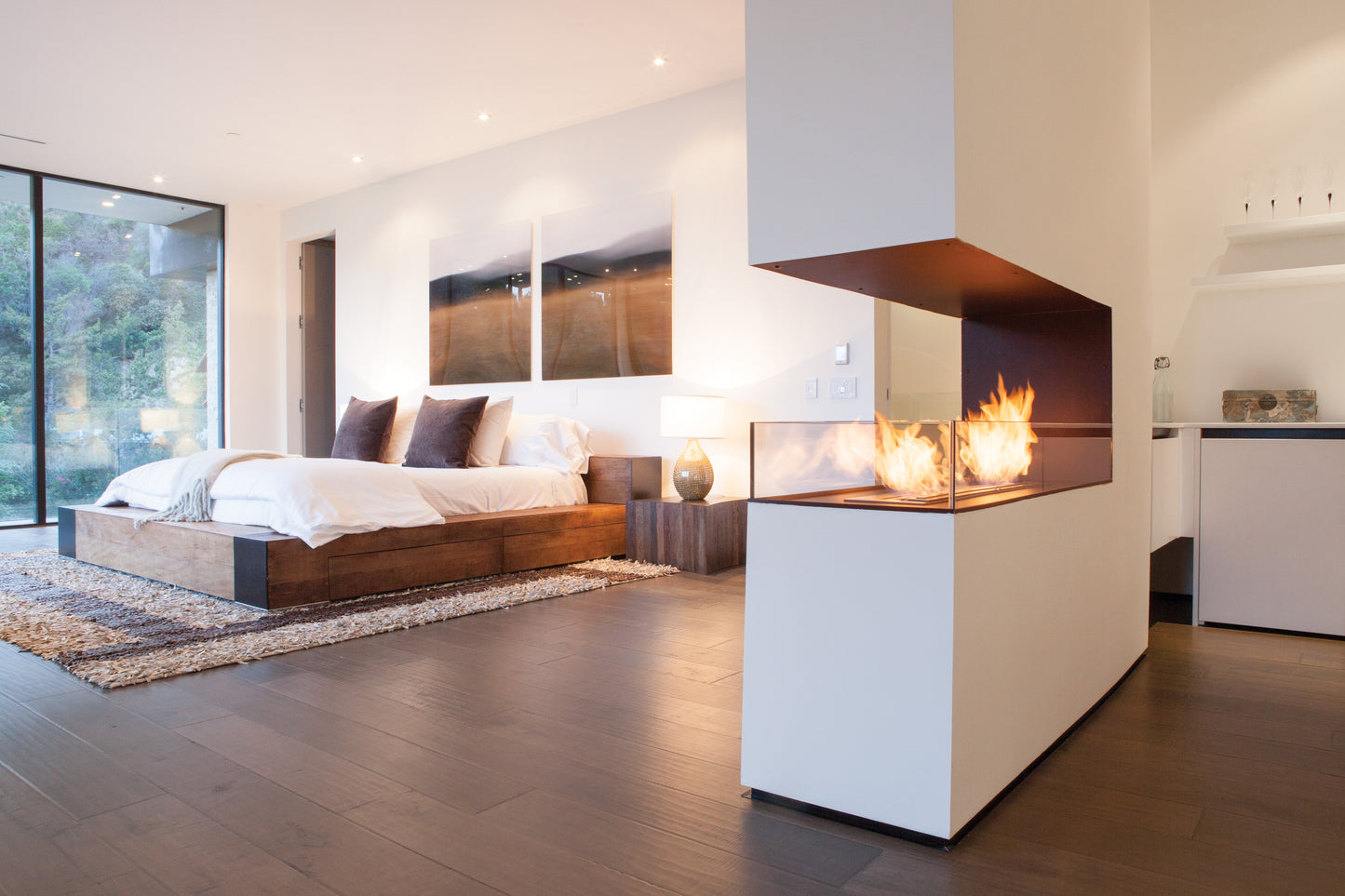 Modern bedroom with a bed, fireplace, and large windows.