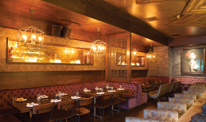 Interior of a restaurant with wooden walls, chandeliers, and red booth seating.