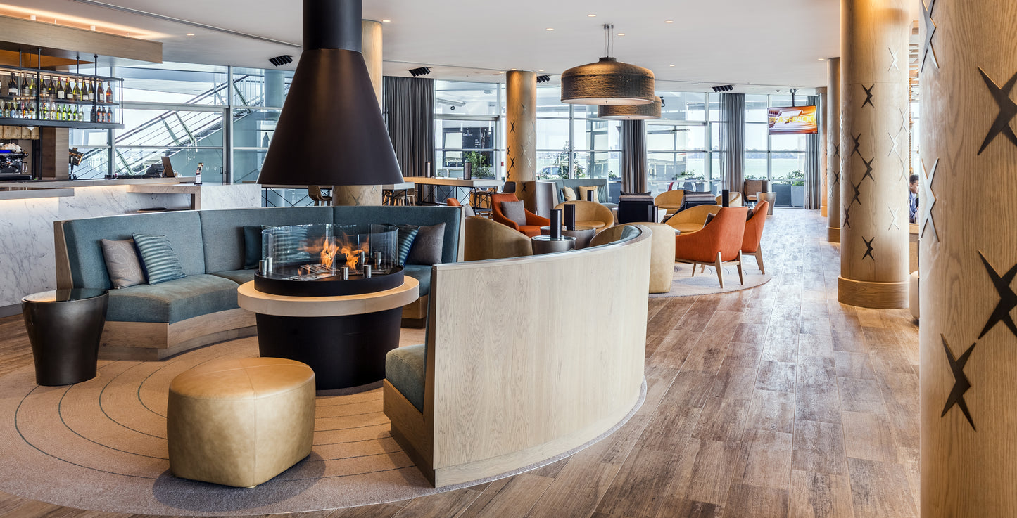 Modern lounge area with a fireplace, couches, and chairs in a well-lit room.