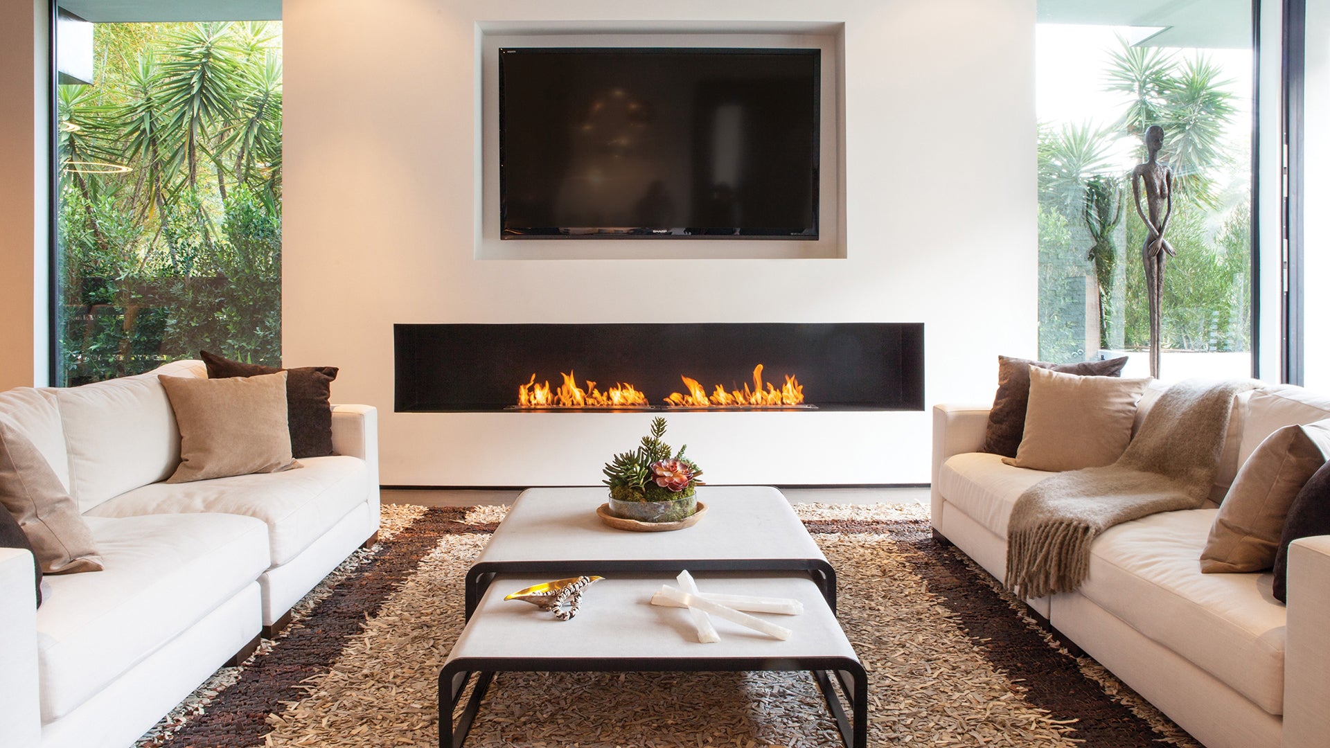 Modern living room with white sofa, coffee table, and wall-mounted TV.