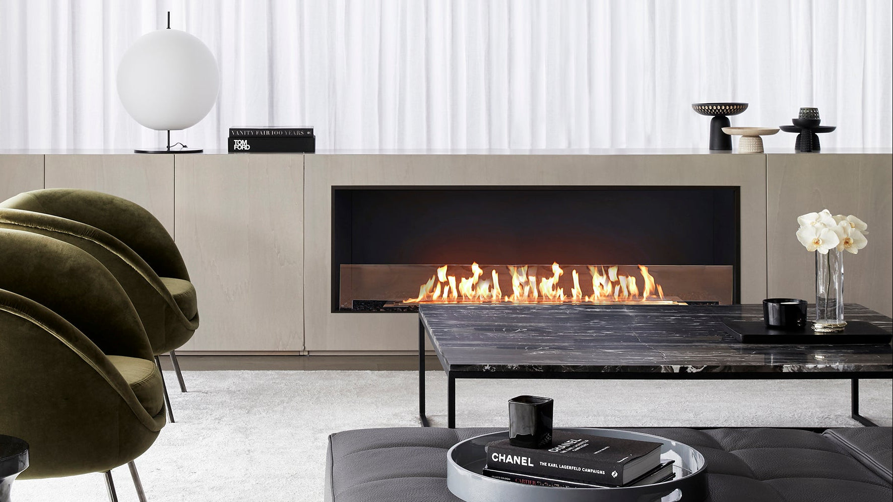 Modern living room with a fireplace, chairs, and a Chanel coffee table.