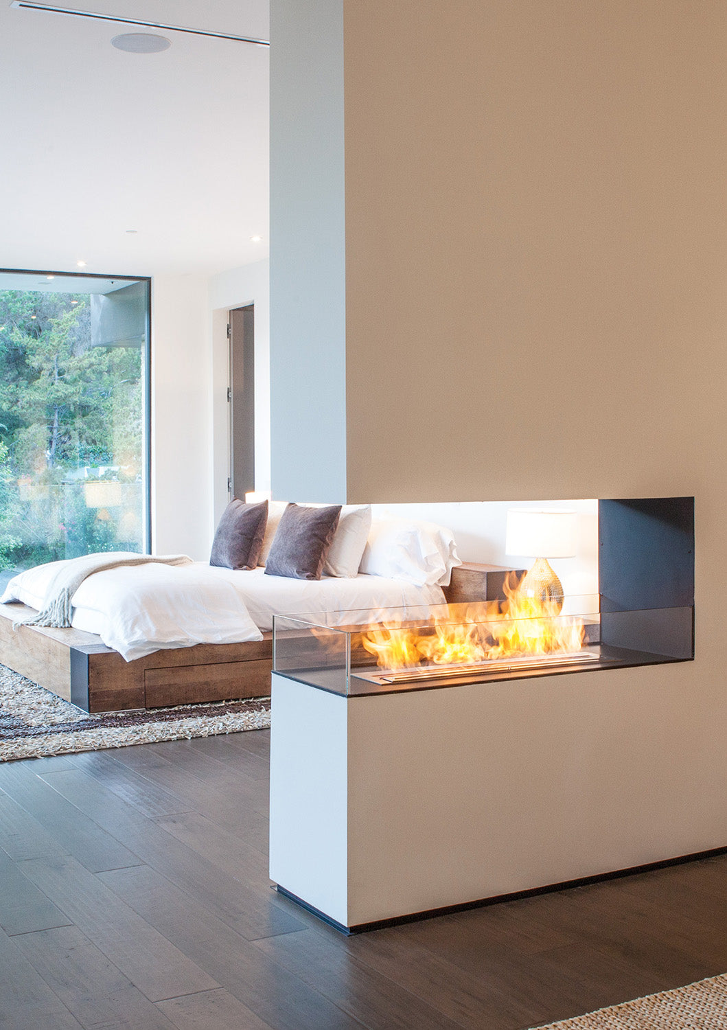 Modern living room with a bioethanol fireplace and a bed in the background